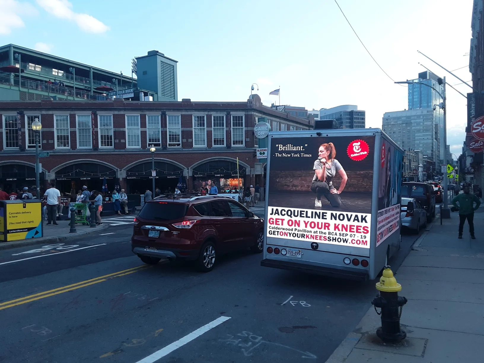 Mobile LED billboard truck advertising Jacqueline Novak’s Get On Your Knees near Fenway Park on a Boston street