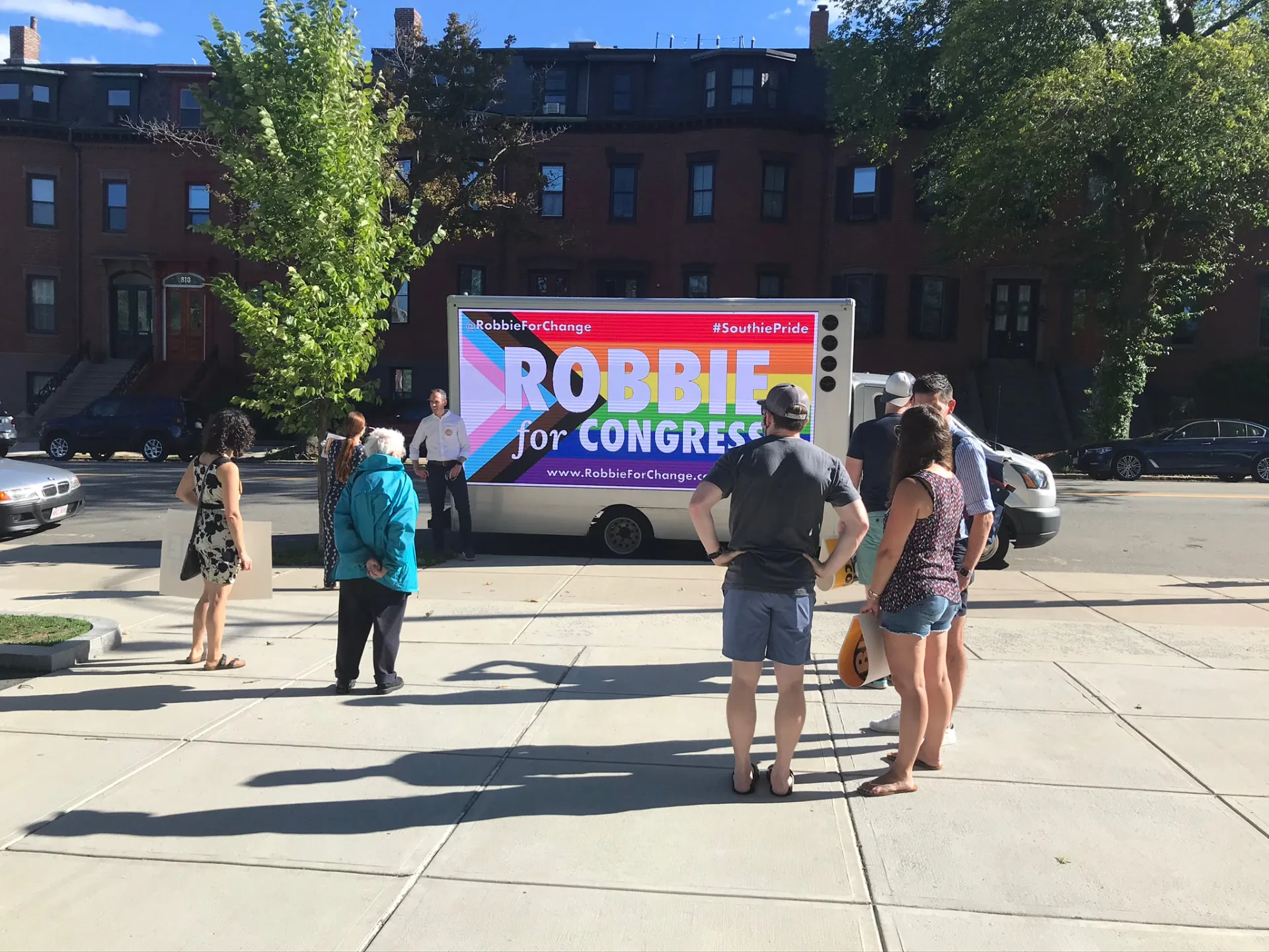 LED billboard truck displaying Robbie for Congress campaign artwork near pedestrians