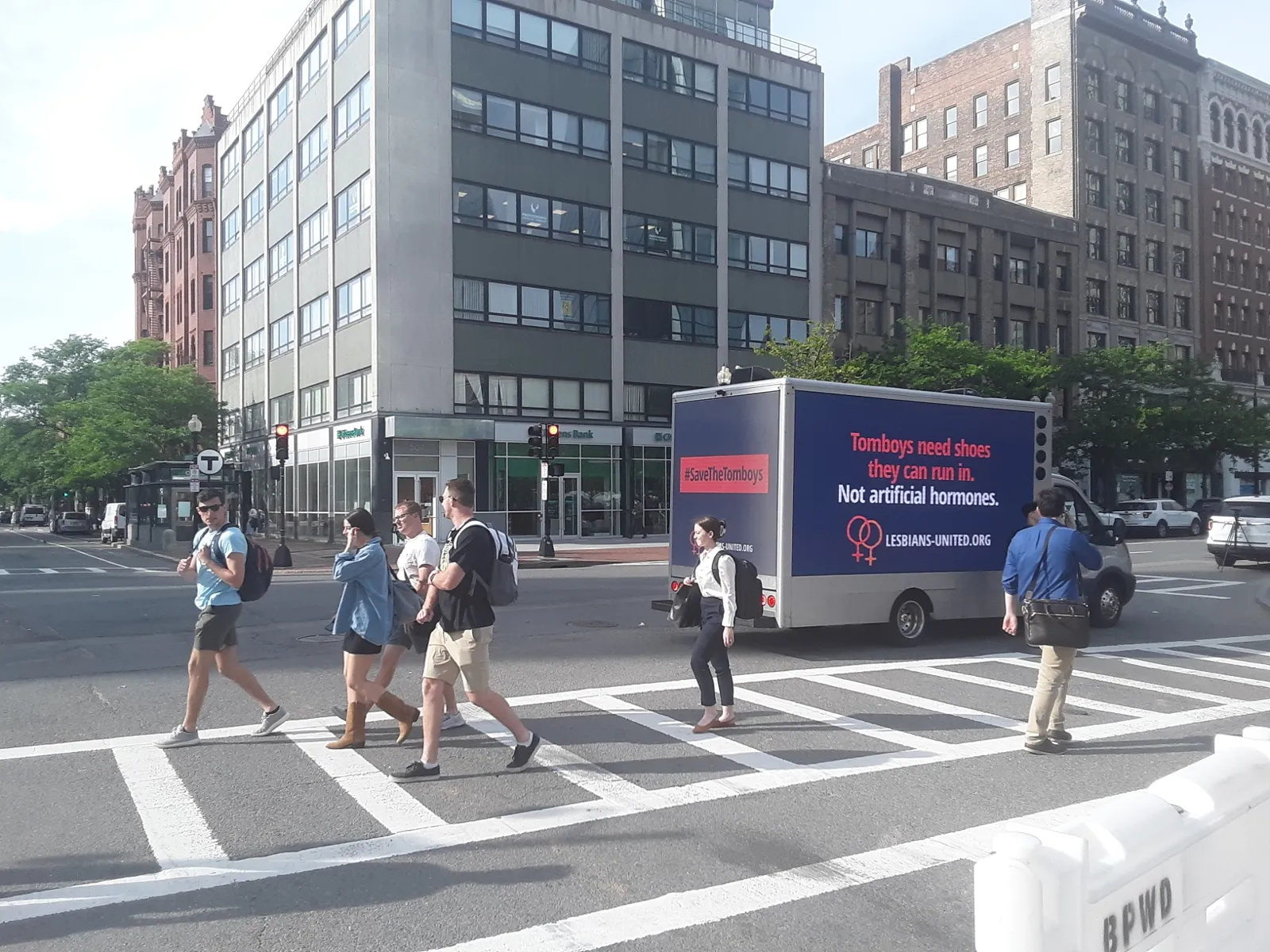 LED billboard truck showing a Lesbians United #SaveTheTomboys message at a busy Boston crosswalk