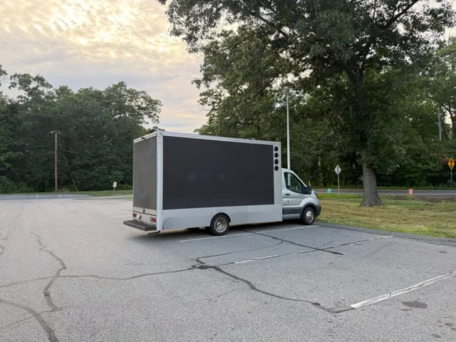 Side view of the used LED billboard truck for sale parked in a lot