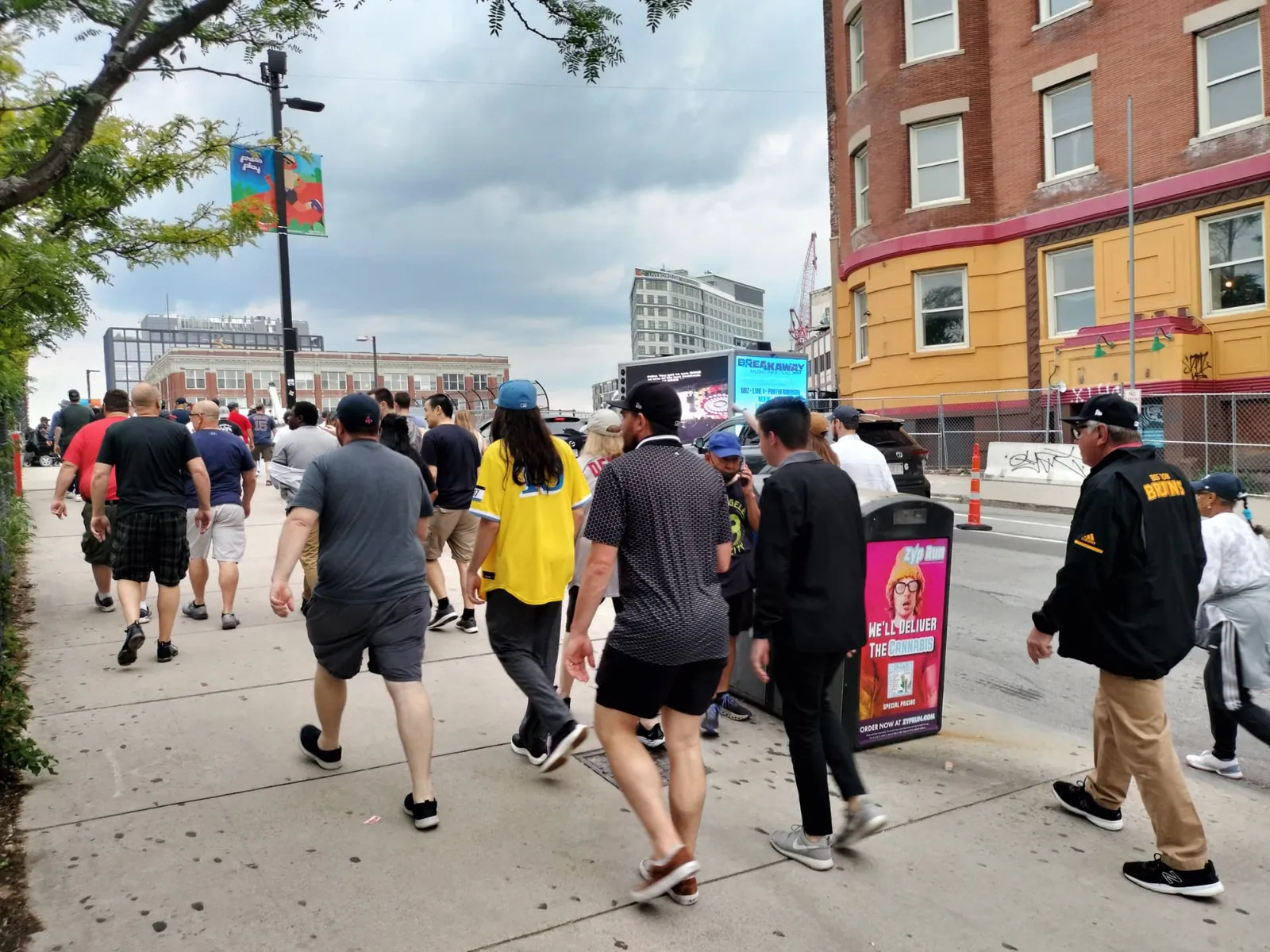 Pedestrians near Fenway passing an LED billboard truck displaying music festival creative