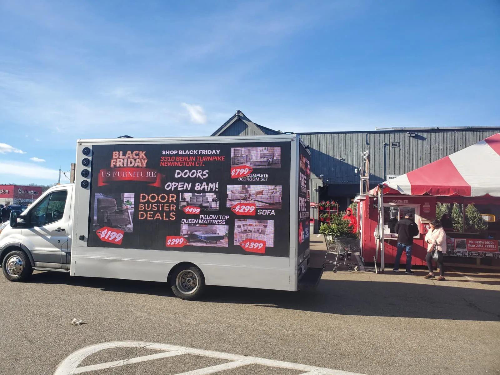 White Ford Transit LED billboard truck displaying furniture store Black Friday doorbuster deals at a retail plaza in Newington, CT