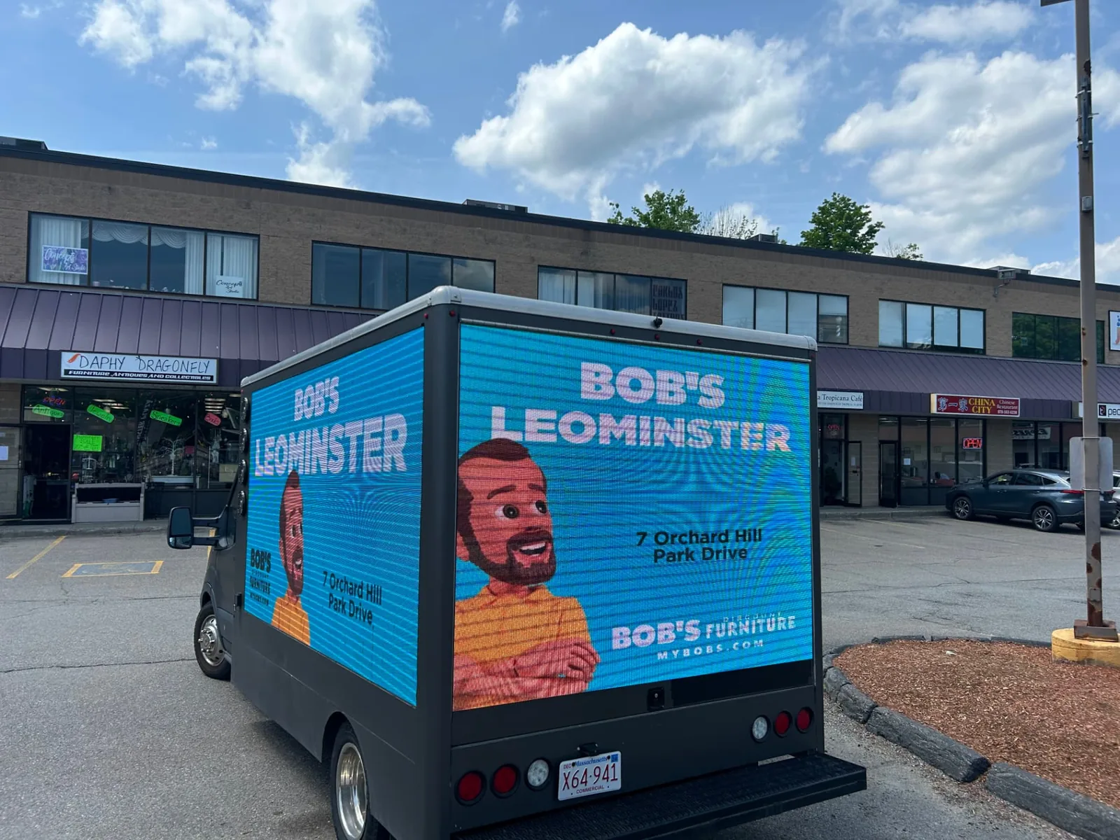 LED billboard truck advertising a furniture retailer store location in a Massachusetts plaza