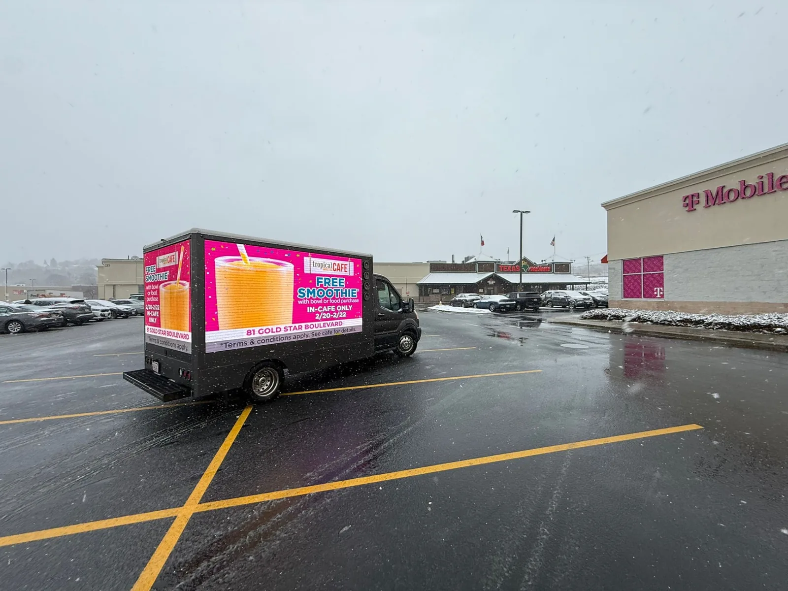 LED billboard truck advertising a retail promotion in a shopping plaza parking lot