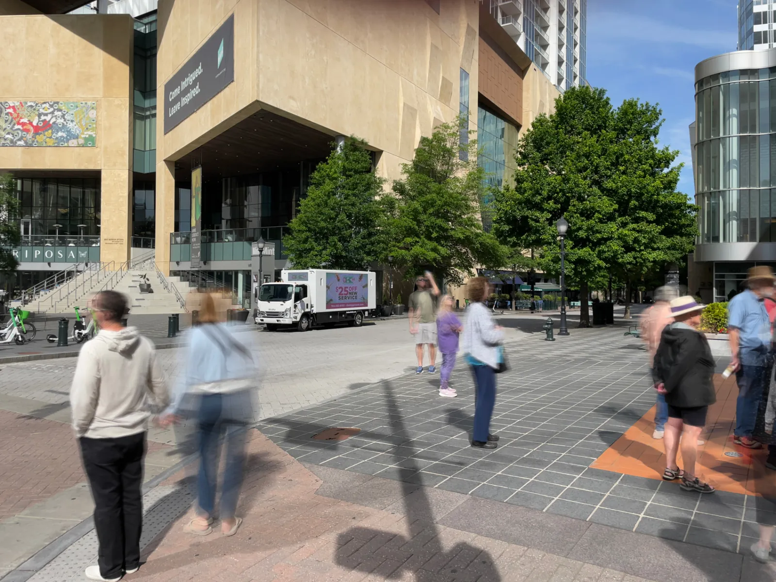 Pedestrians walking past an LED billboard truck parked near the Mint Museum in Charlotte