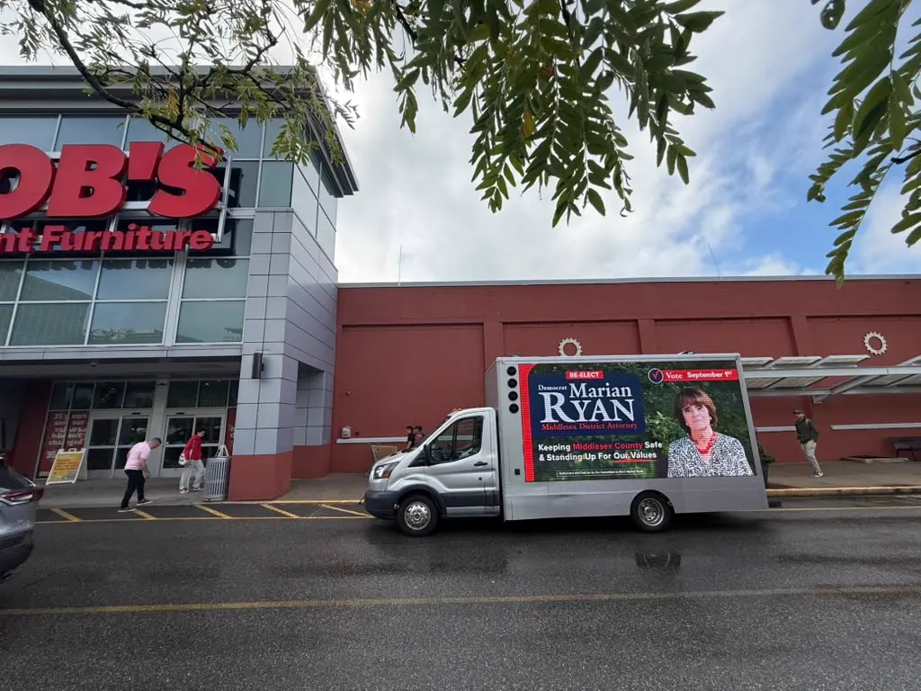 Marian Ryan for Middlesex District Attorney LED billboard truck parked outside Bob's Discount Furniture in a Middlesex County retail plaza