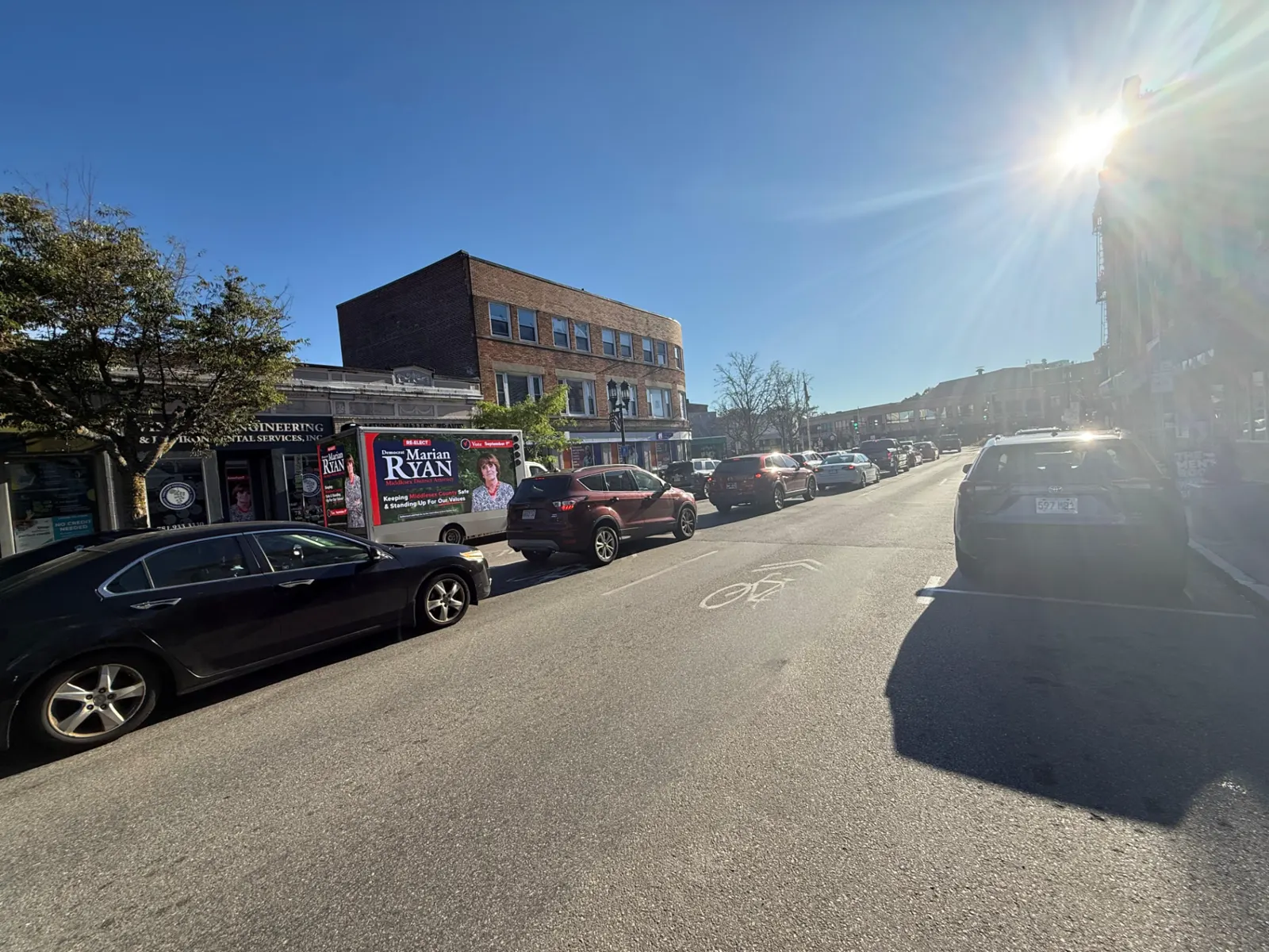 LED billboard truck displaying the Marian Ryan Middlesex District Attorney campaign ad in daytime traffic along a Middlesex County retail district