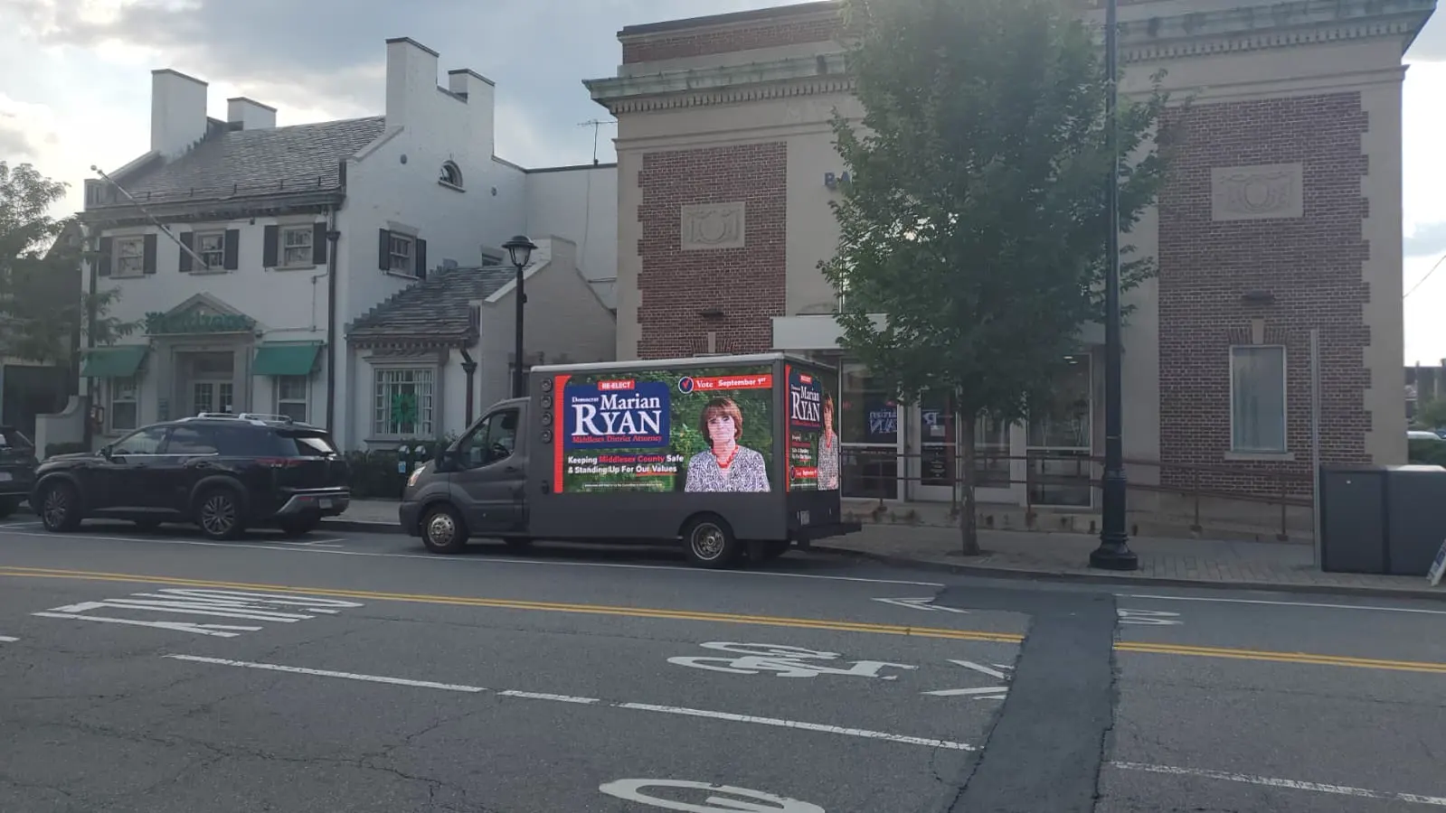 Marian Ryan mobile billboard truck parked on a downtown Middlesex County main street near local banks and storefronts