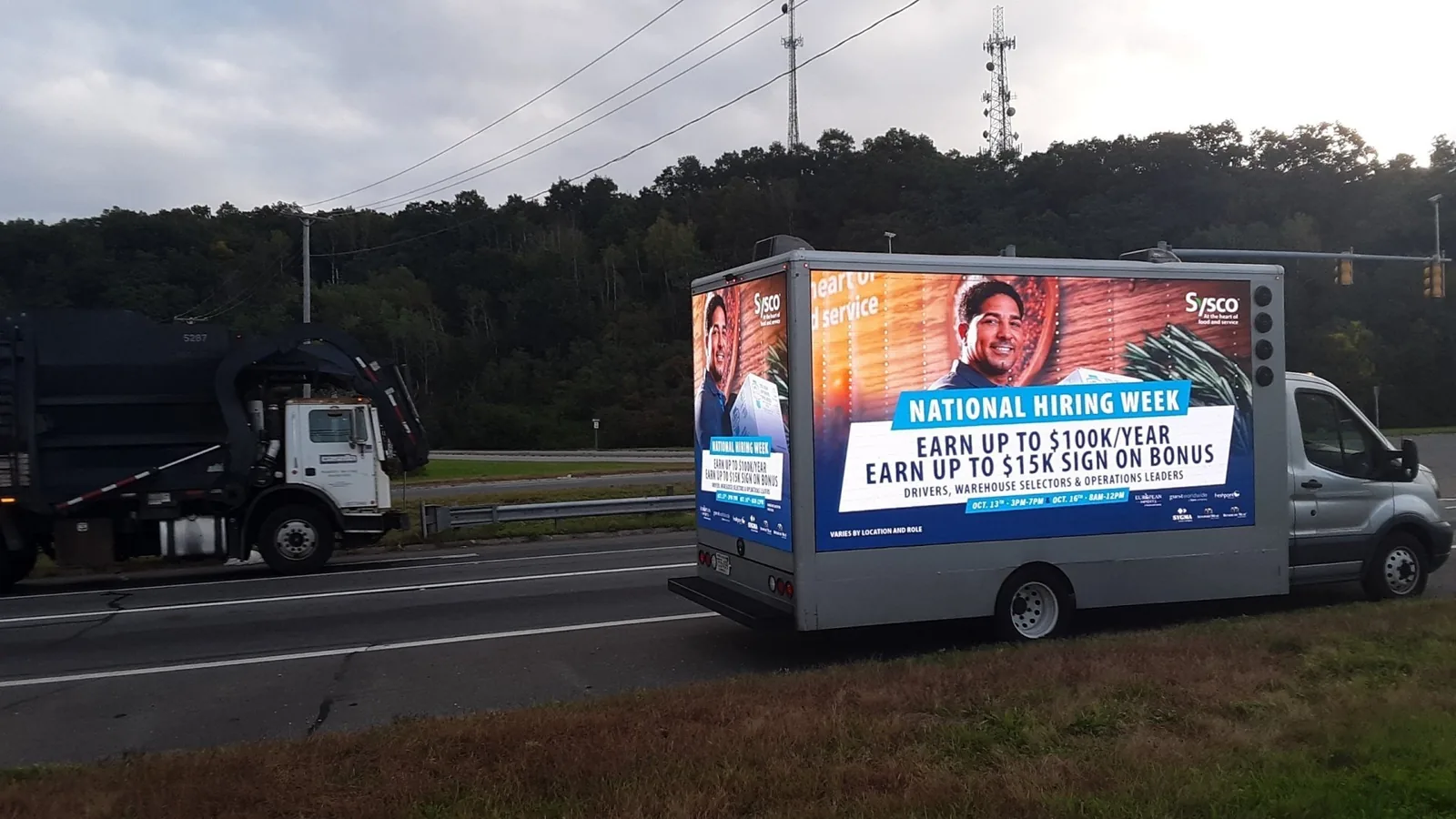 Mobile billboard truck running a national hiring week recruitment ad along a highway