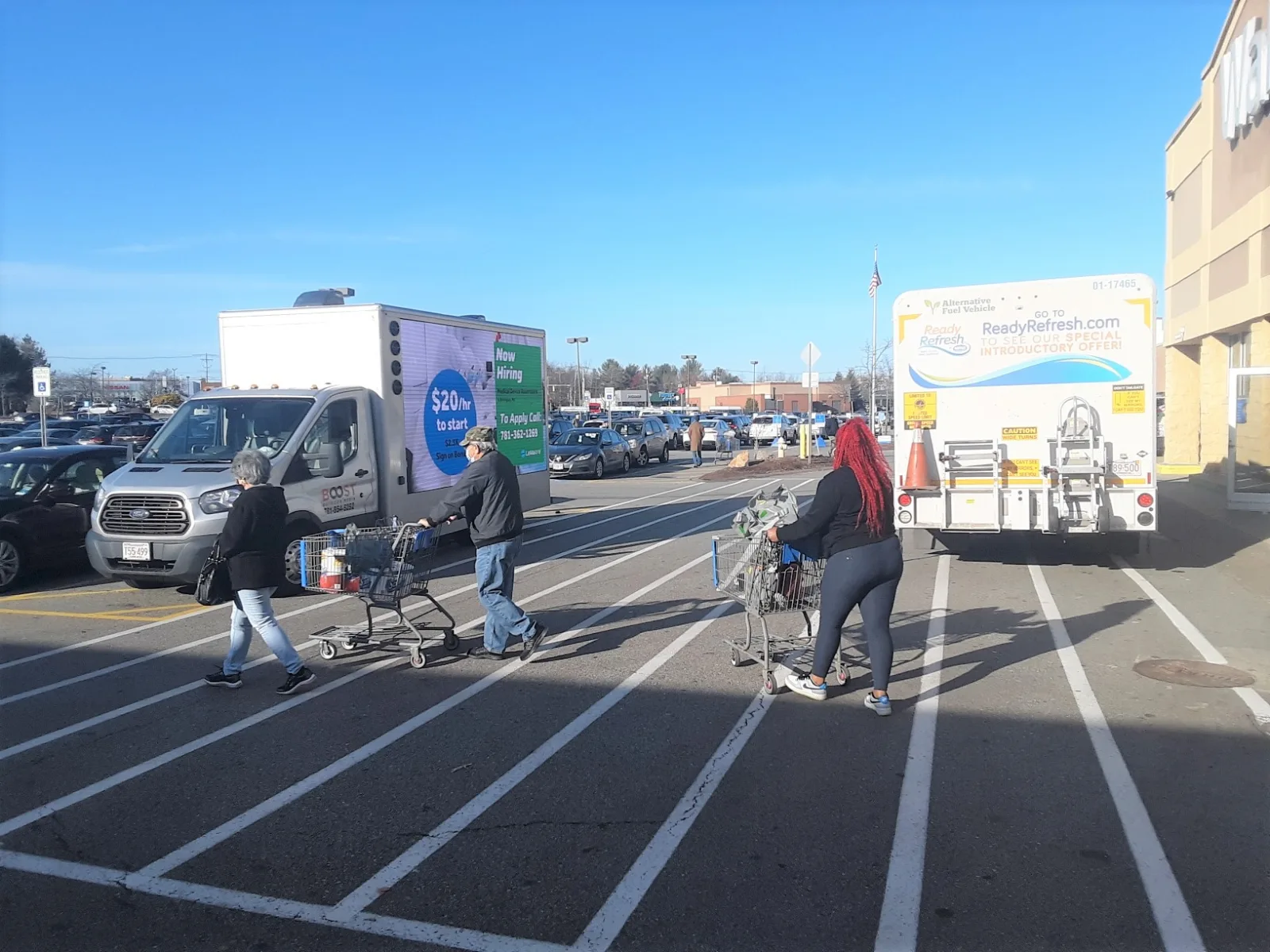 LED billboard truck running a hiring campaign in a busy big-box retail parking lot as shoppers walk past with carts