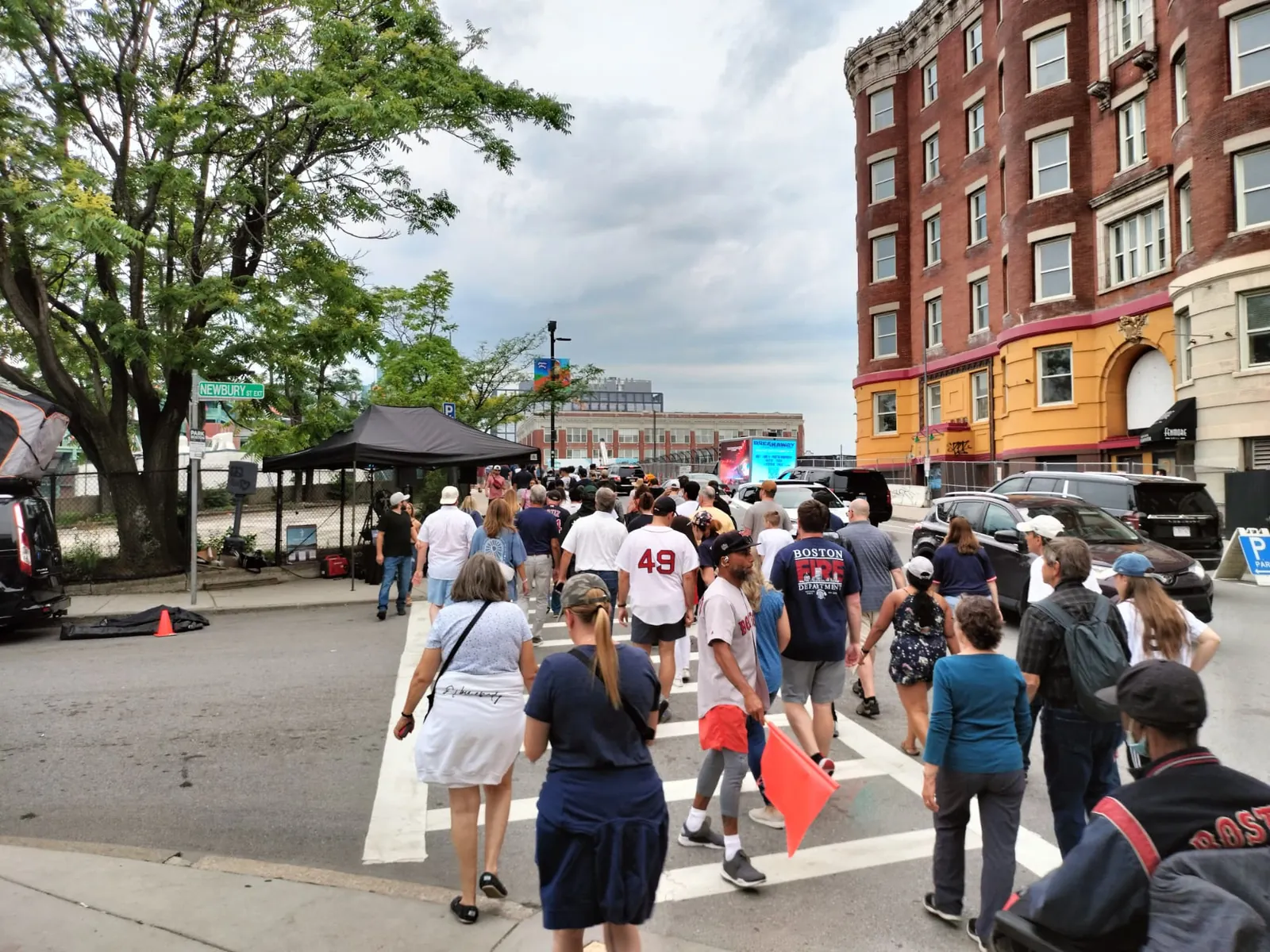 Crowds walking to a Red Sox game past a mobile LED billboard truck advertising a music festival