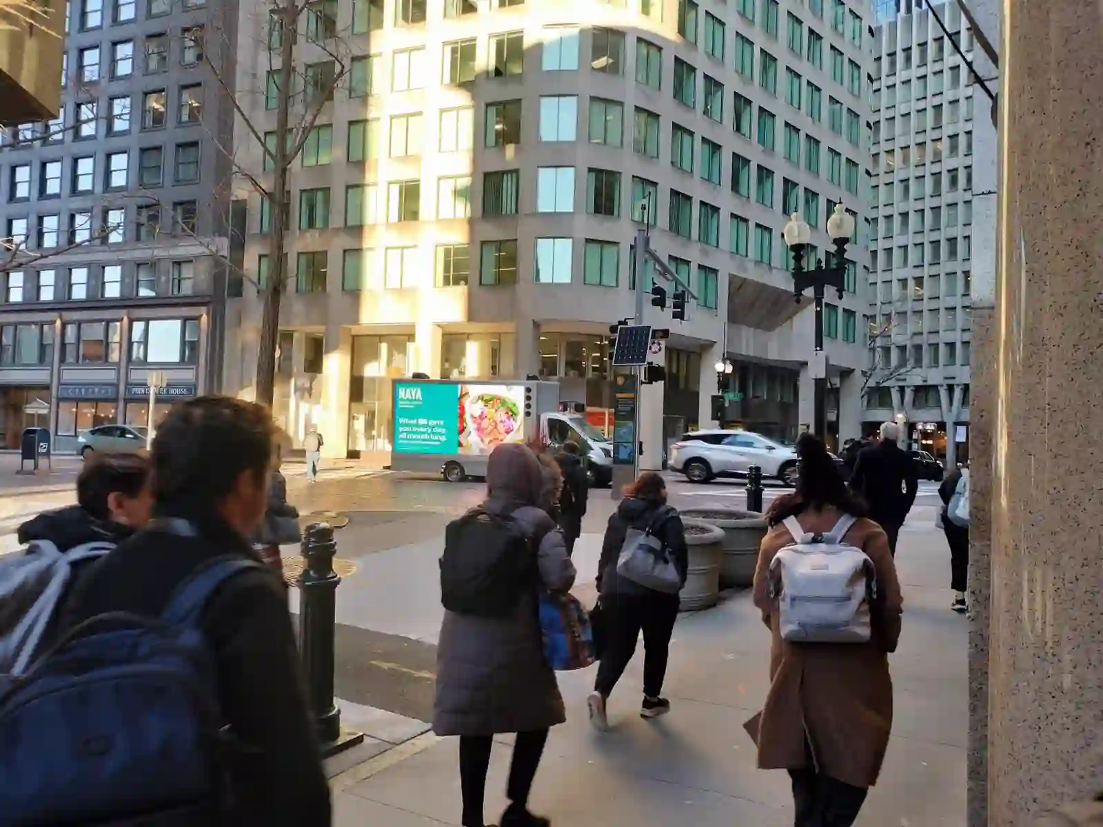 Naya LED billboard truck driving through downtown Boston Financial District among office workers and pedestrians