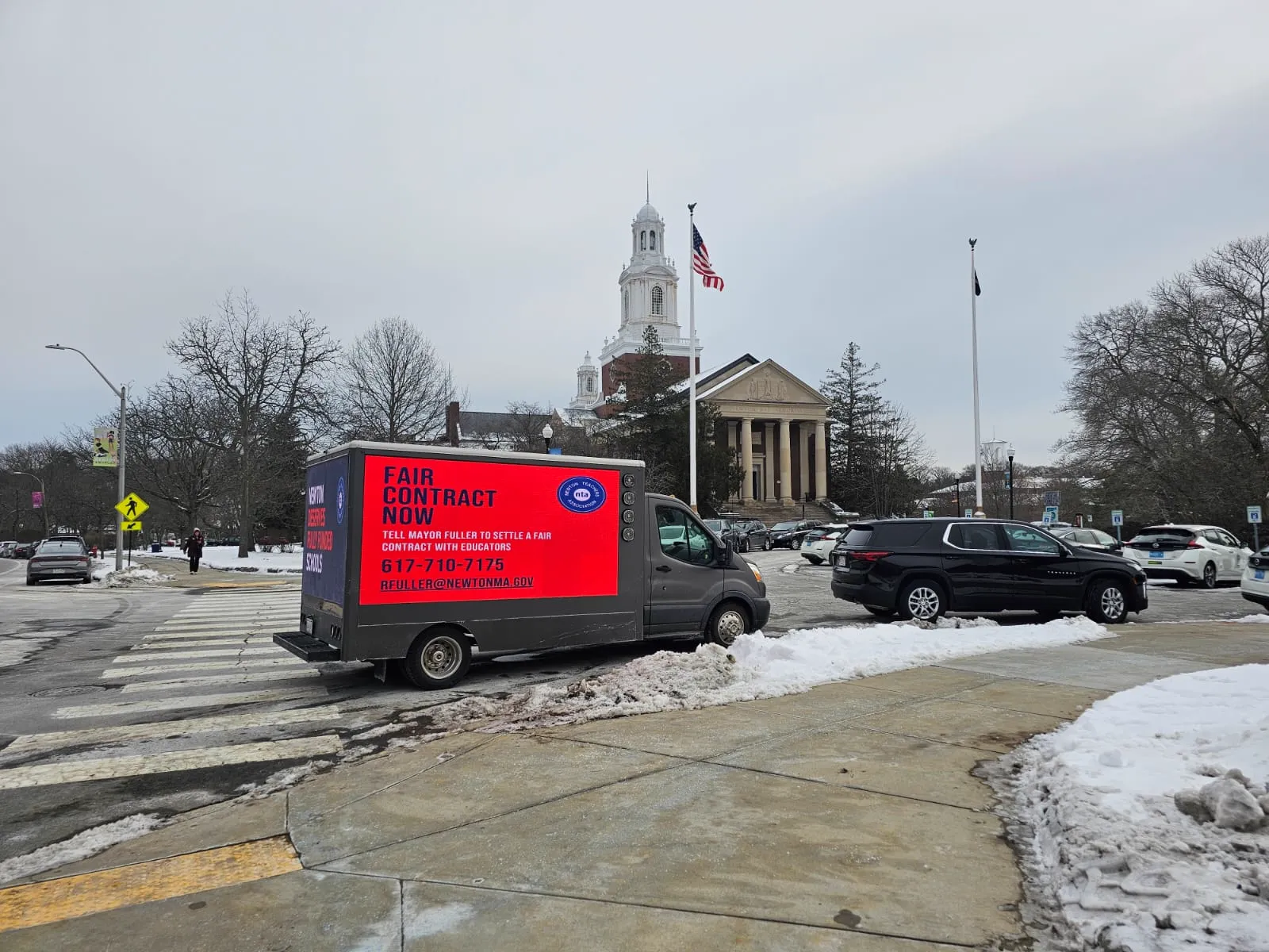 Mobile LED billboard truck showing Fair Contract Now with a call to contact the mayor, driving past Newton City Hall in Newton, MA