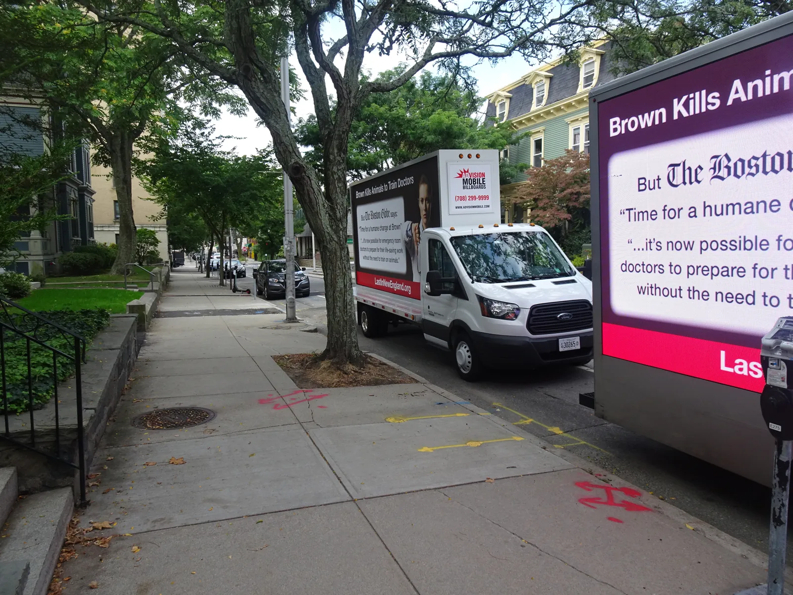 Pedestrians on a Providence sidewalk next to a nonprofit mobile billboard advertising truck