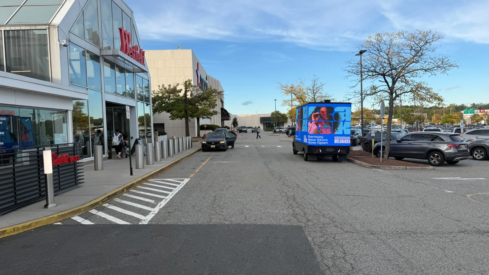 Nordstrom Rack LED billboard truck along a shopping-center storefront lane during Boost Outdoor Media’s retail grand-opening campaign