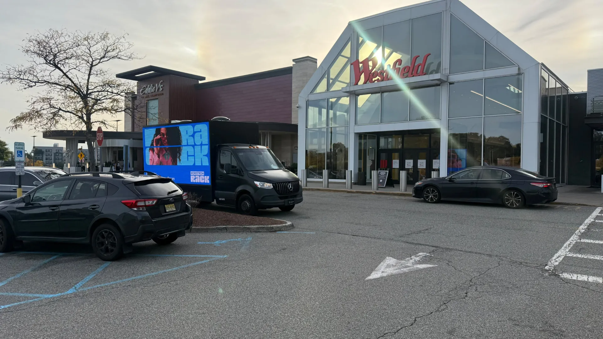 Nordstrom Rack campaign LED billboard truck outside a TJ Maxx storefront in a retail shopping center