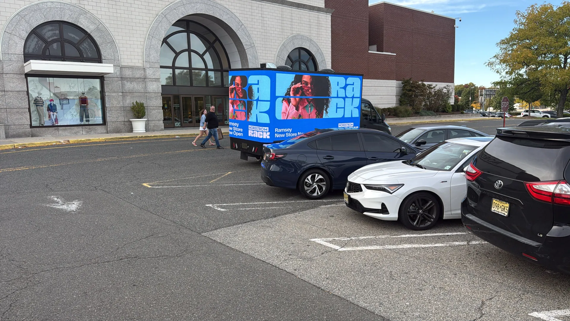 Nordstrom Rack rear LED billboard display beside parked cars and retail storefronts during Boost Outdoor Media’s grand-opening campaign
