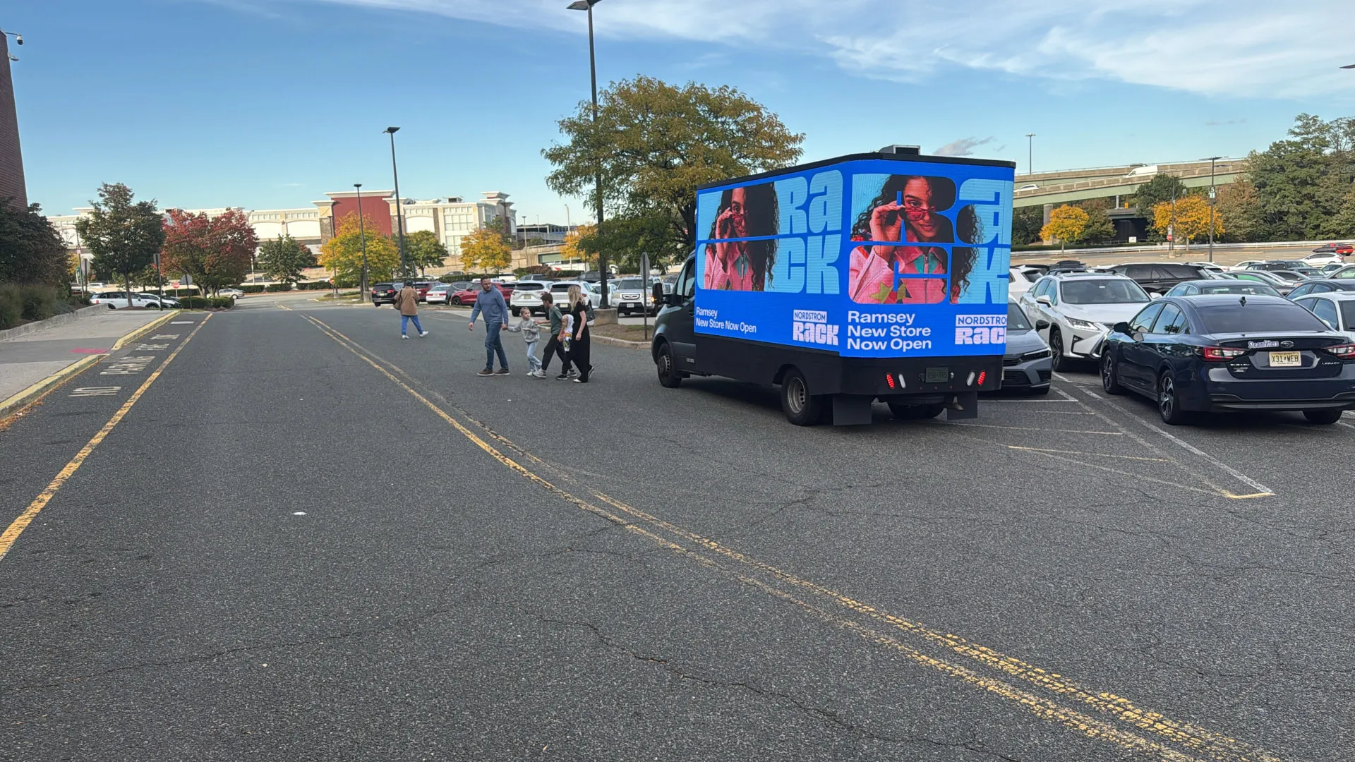 Nordstrom Rack LED billboard truck in a shopping-center parking area with nearby pedestrians during the retail campaign