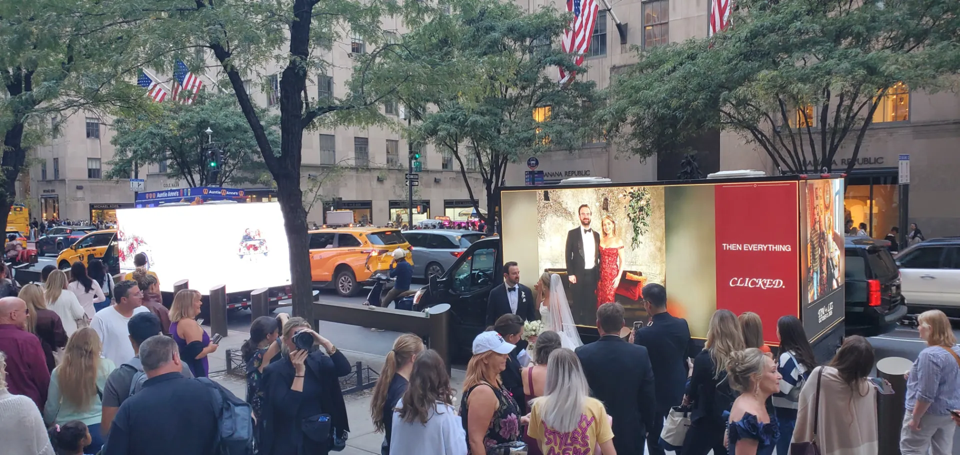 Two LED billboard trucks showing custom wedding photos to a crowd on Fifth Avenue near Rockefeller Center NYC