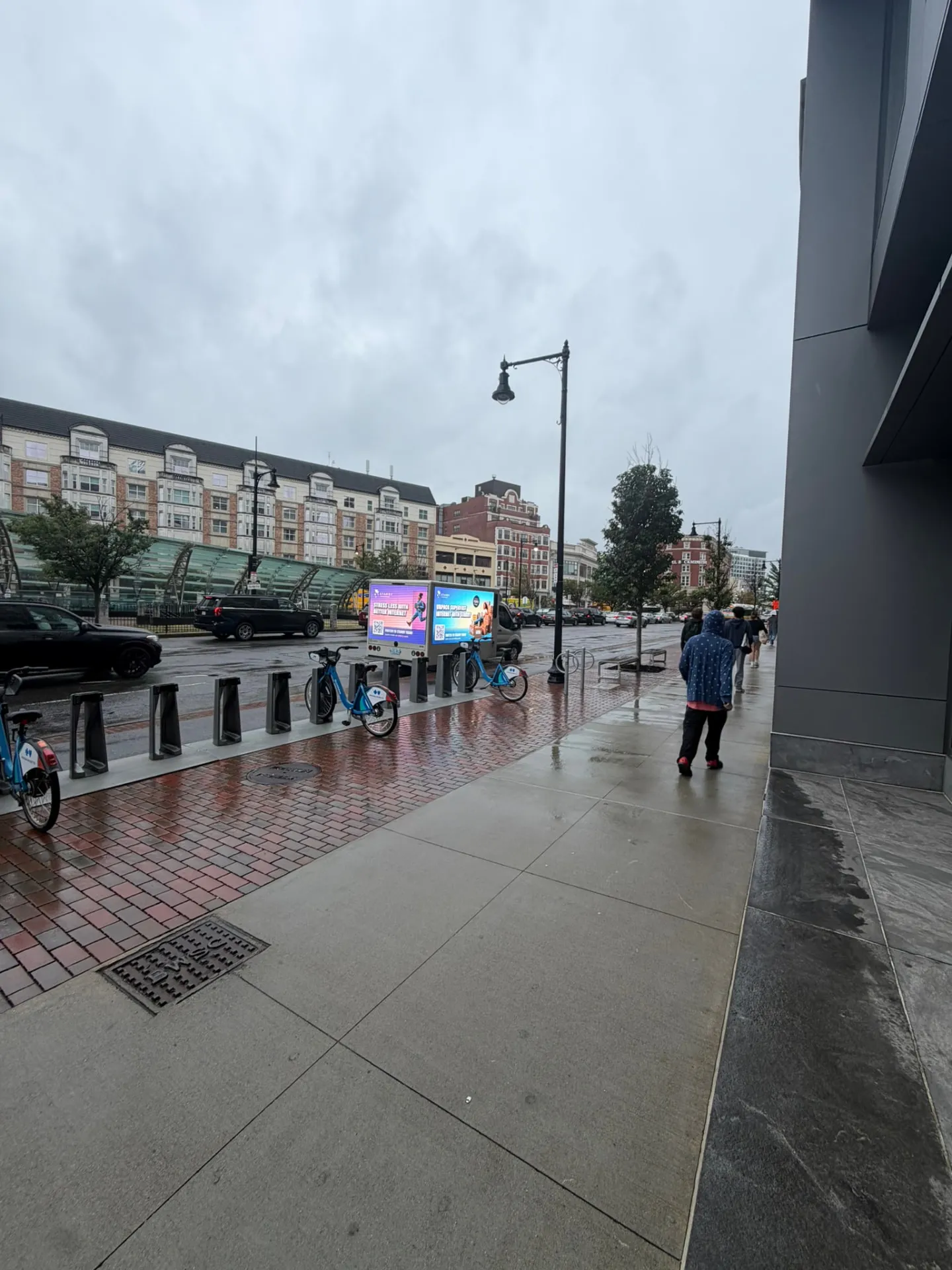 Starry LED billboard truck with both screens lit near the Bluebikes station in Fenway Boston on a rainy day