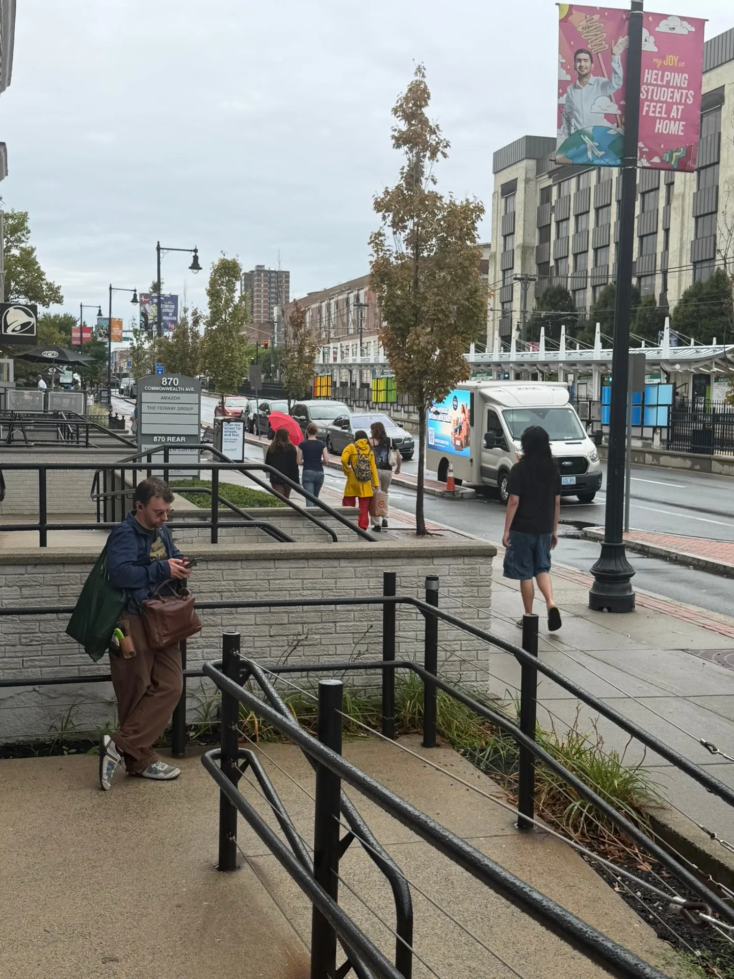 Starry LED billboard truck parked on Commonwealth Avenue near Boston University with students walking past the Green Line stop