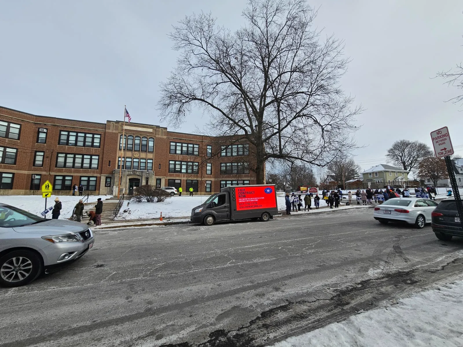 Mobile billboard truck with Fair Contract Now message parked in front of a Newton school during the teachers strike in winter