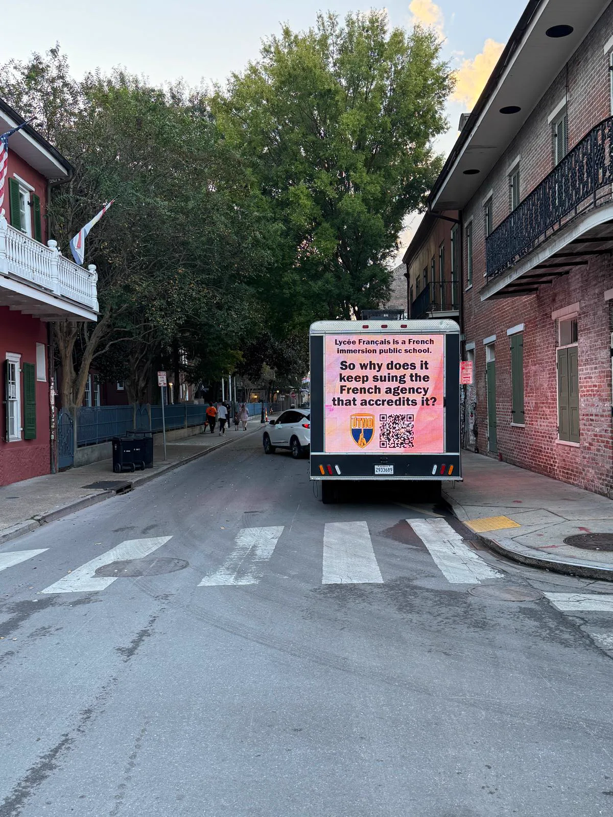 UTNO mobile billboard truck on a French Quarter street in New Orleans displaying the union's message about Lycée Français