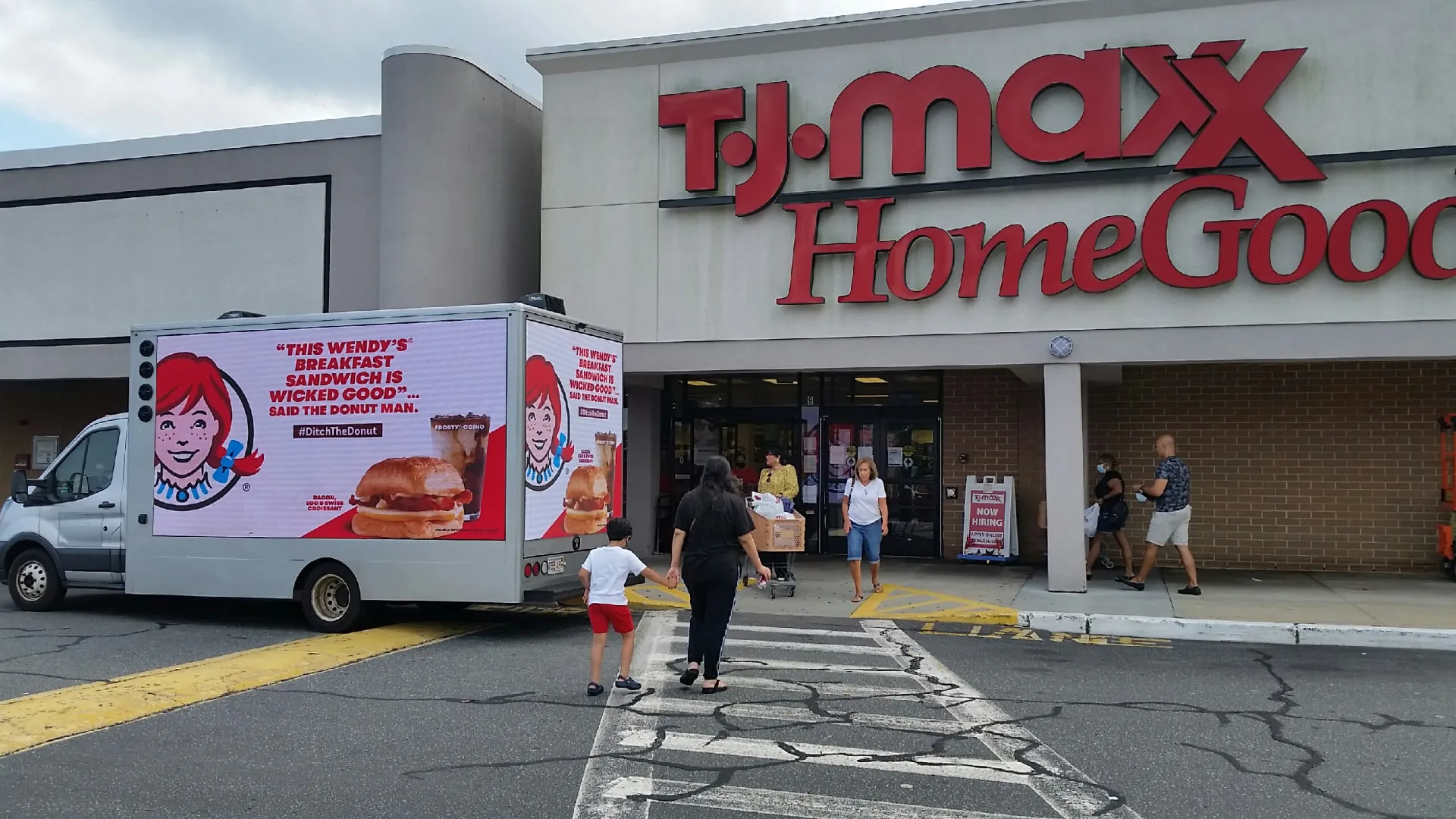 Wendy's breakfast LED billboard truck parked outside a TJ Maxx HomeGoods store with shoppers walking past
